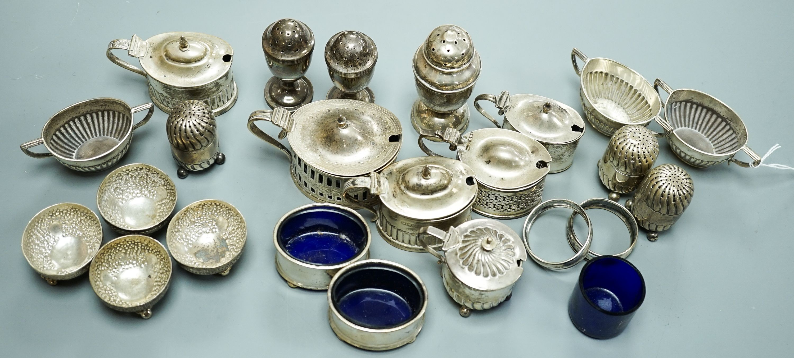 A mixed group of assorted mainly early 20th century silver condiments, including mustard pots, salts and pepperettes, two napkin rings and four plated salts, some lacking liners.
